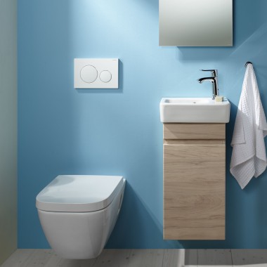 Pie sienas piekarināms Renova Plan WC un izlietnes zona, kas piestiprināta pie gaiši zilas sienas Pie sienas piekarināms Renova Plan WC un izlietnes zona, kas piestiprināta pie gaiši zilas sienas