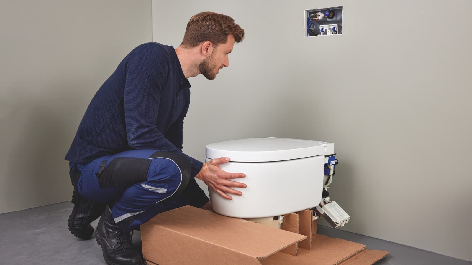 Sanitārais speciālists uzstāda Geberit AquaClean Sela bidē tualetes podu Sanitārais speciālists uzstāda Geberit AquaClean Sela bidē tualetes podu